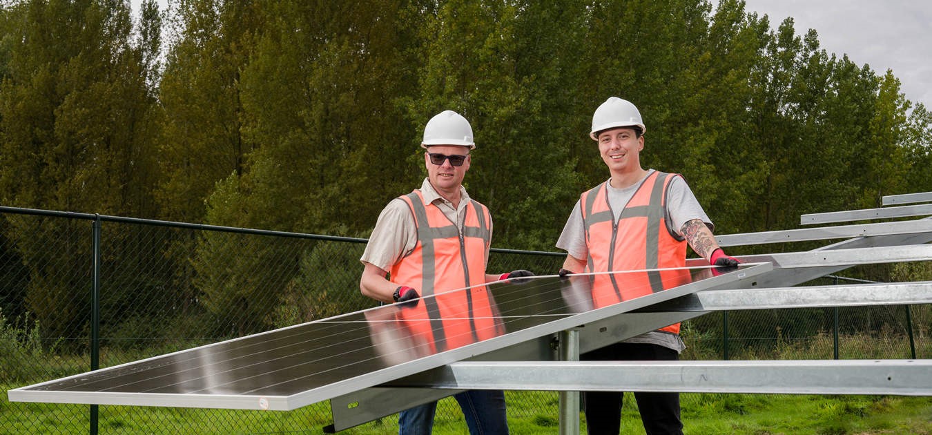 Henk Haaksema en Mees Tijssen (PowerField) leggen het eerste zonnepaneel - Zonnepark-Zevent.JPG